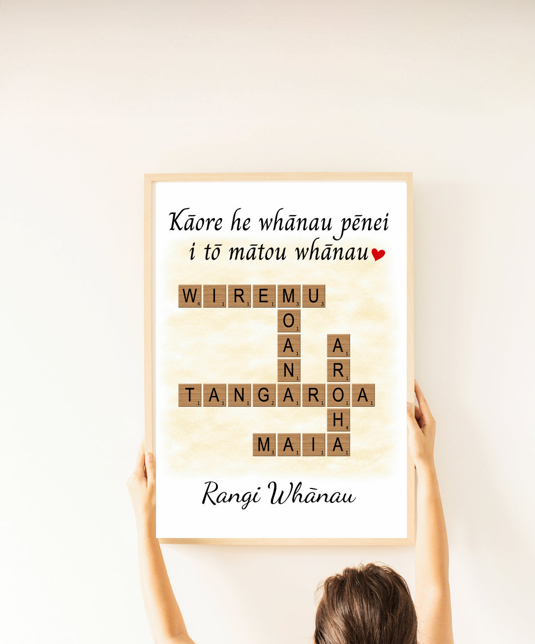 Person holding a framed poster with text and Scrabble-style letters on a light background